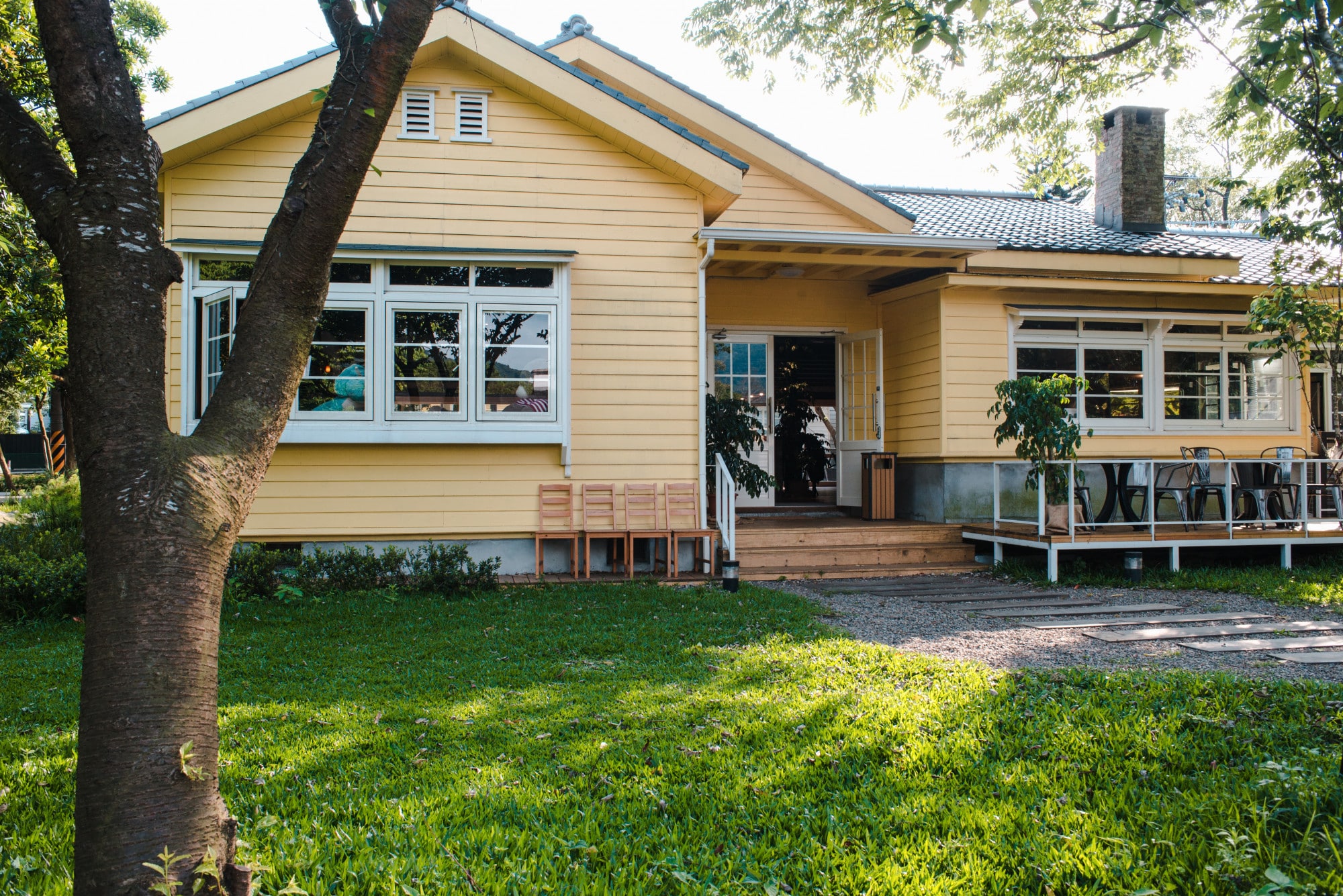 charming-yellow-house-with-wooden-windows-green-grassy-garden-min